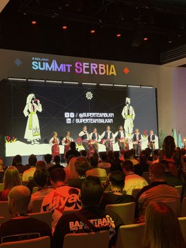 A conference audience watching a 'YugaLabs Summit Serbia' presentation on a large screen, featuring speakers on stage.