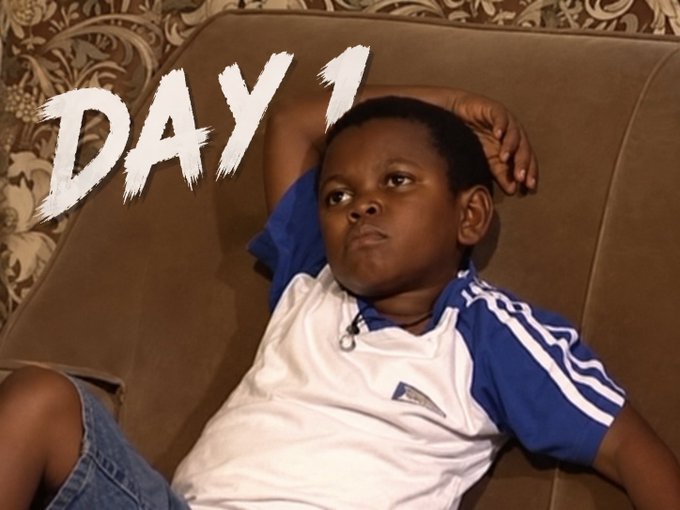 The image shows the text "DAY 1" overlaid on a young boy lounging on a brown couch. This relates to the accompanying post by showing the "first day" of waiting for a giveaway from "@blknoiz06" related to the ticker "$ANSEM."