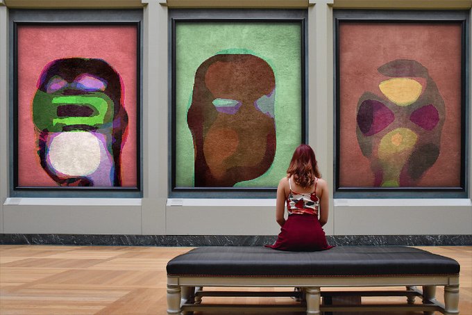 A woman in a red and white top sits on a bench viewing three large, colorful abstract paintings displayed in a gallery.
