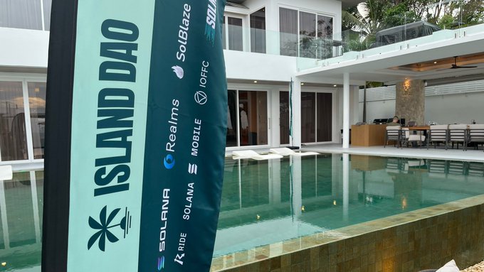 The image features an advertisement for a company called Island Dao, which has a white house with a pool in the background. The advertisement includes a banner that says "Island Dao" and "Solana dApp". It also mentions that there are builders who want to ship apps to the Solana dApp Store. The image is related to the post because it promotes Island Dao, which is a company that specializes in creating mobile applications for the Solana cryptocurrency.