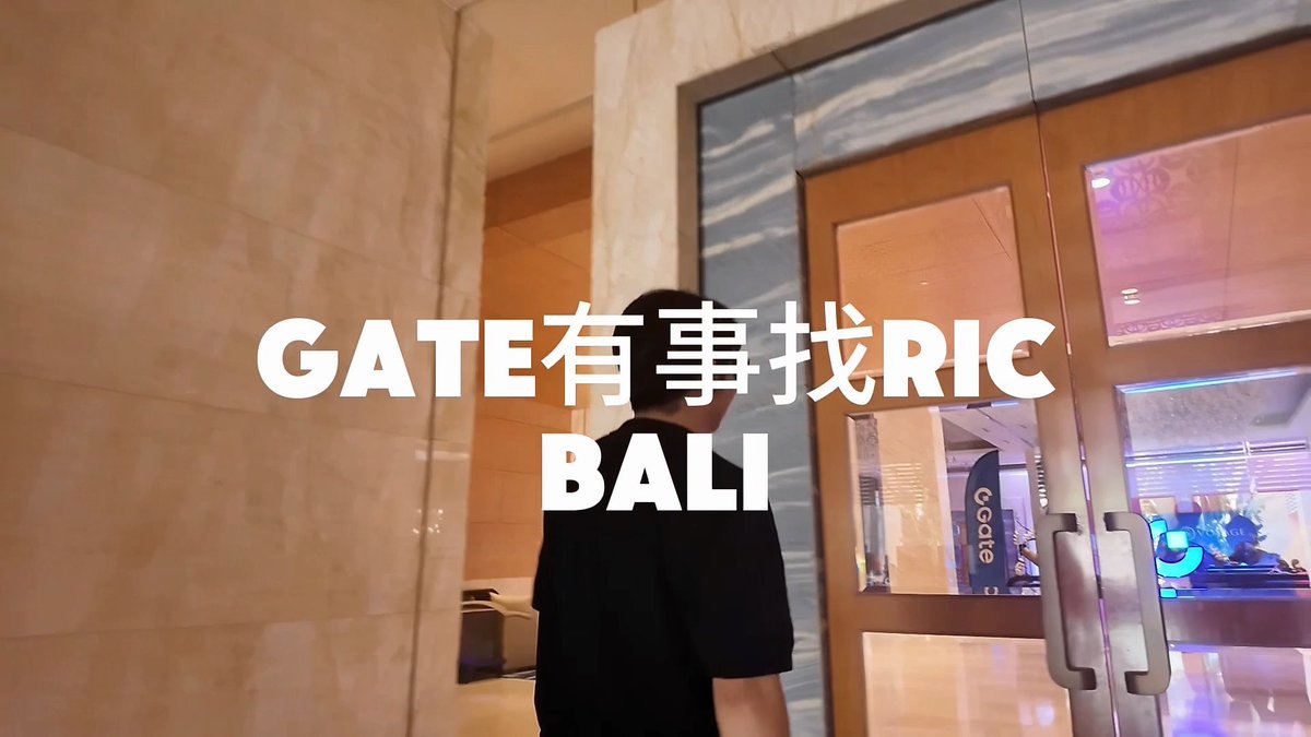 A person in a black shirt walks through elegant doors in a marble lobby, overlaid with the text "GATE有事找RIC BALI".
