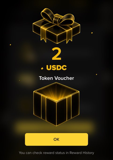 A dark reward screen displays a golden gift box above a glowing open box, with the text '2 USDC Token Voucher', an 'OK' button, and a message reading 'You can check reward status in Reward History'.