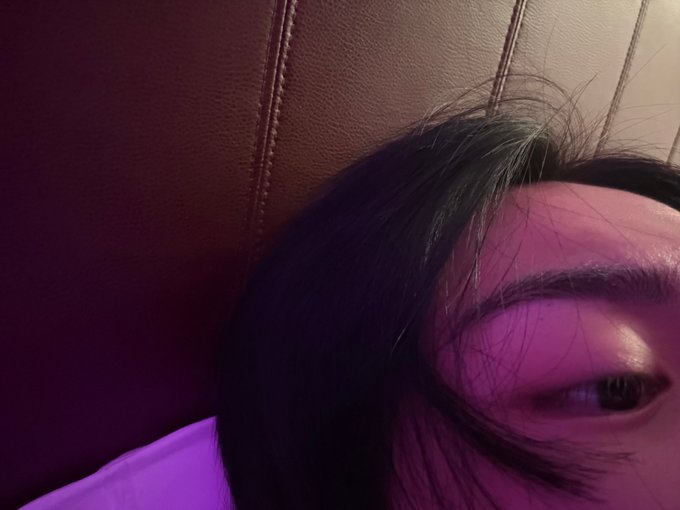 A close-up selfie shows the upper right portion of a person's face, with one eye looking sideways, dark hair falling over their forehead, and a brown leather-textured background with purple lighting. The intimate, dimly-lit portrait corresponds to the personal, private nature of the post's mention of a date (260814) and a direct message exchange.