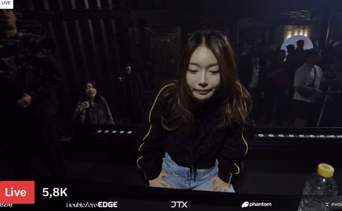 A live stream screenshot showing a young woman with long brown hair, with 'LIVE' indicator and '5,8K' viewers visible along with sponsor logos including 'JTB', 'EDGE', 'JTX', and 'phantom'.