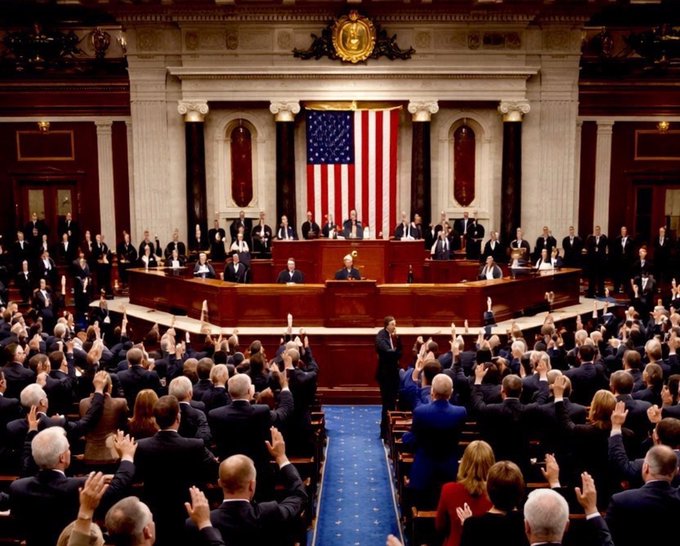 A formal session of the U.S. House of Representatives or Senate chamber is shown, with members applauding as officials stand at the central podium beneath a large American flag. The image visually reinforces the post's message about the Clarity Act approaching its critical August 7 deadline, depicting the legislative body where the consequential crypto regulation vote will take place within the remaining 20 working days.