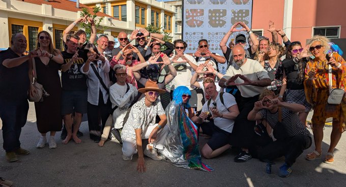 The image shows a group of people posing for a photo, with some holding up their hands as if they are making peace signs or writing love letters. The text "My heart is l filled with glittering cosmic glue. I will write a appreciation threat later. For Now: We did something real. That's rarer than you think." suggests that the group has accomplished something significant, possibly related to art or creativity. The post seems to be promoting an appreciation for their work and expressing gratitude towards them.