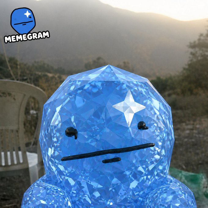 A faceted blue diamond-shaped character with a neutral expression is pictured against a mountain sunset backdrop, with a "MEMEGRAM" logo in the upper left corner. The image ties to the "$GRAM" post by visually branding the meme character as the project's mascot, reinforcing its "diamond hands" theme.