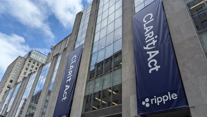 Two blue banners reading 'Clarity Act' and featuring the Ripple logo hanging on the side of a glass-paneled building.