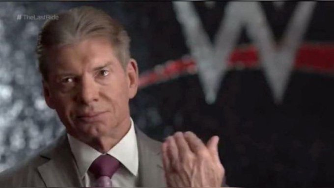 Vince McMahon in a gray suit and burgundy tie claps with a serious expression in front of a WWE logo backdrop, with the hashtag #TheLastRide visible in the corner.