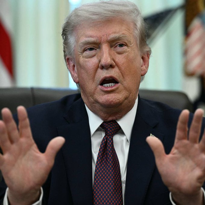 A man in a dark suit and red tie gestures with both hands raised while speaking, seated in what appears to be the Oval Office with an American flag in the background. The image relates to the accompanying post about Trump's Bitcoin holdings and potential gains from increased cryptocurrency investment.