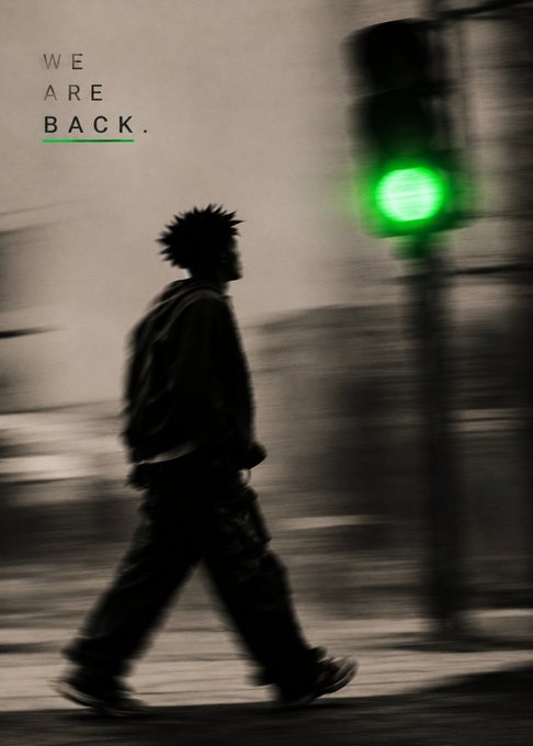 An artistic photo of a silhouetted figure with spiky hair walking in front of a green traffic light, with the text 'WE ARE BACK.' displayed in the upper left corner.