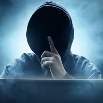 A dark, mysterious image of a hooded figure with their face obscured, pressing a finger to their lips in a 'shh' gesture, with laptop edge visible at the bottom.