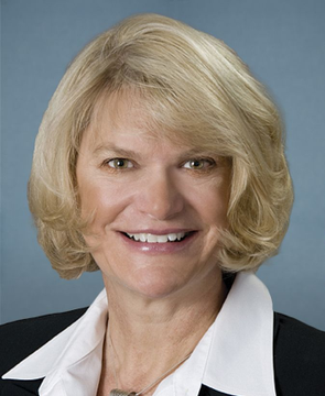 The image shows a professional headshot of a smiling blonde woman in a black blazer with a white collared shirt, appearing to be a formal portrait of Senator Cynthia Lummis, who is referenced in the news about the CLARITY Act and crypto asset protections.