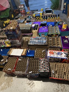 Floor display of numerous crates and boxes containing what appears to be bottles of alcohol or beverages at a market or shop.