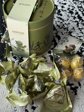 The image features a green box with Chinese characters, which appears to be a gift box or container for coins. The box has been opened, revealing its contents inside. There are several small packages of candy scattered around the box, adding to the overall presentation. A note is also present in the scene, possibly providing information about the items inside the box.