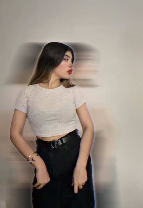 A woman with long dark hair poses in a fitted white ribbed crop top and high-waisted black jeans with a belt, her gaze turned to the side against a plain wall with subtle shadow effects. The image's dreamy, soft-focus aesthetic complements the contemplative tone of the caption, evoking a quiet, introspective mood about affection and longing.