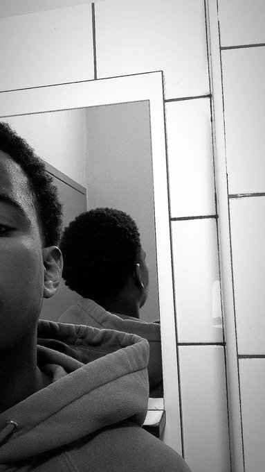 Black-and-white mirror selfie of a person wearing a hoodie, showing the back of their head reflected in the mirror.