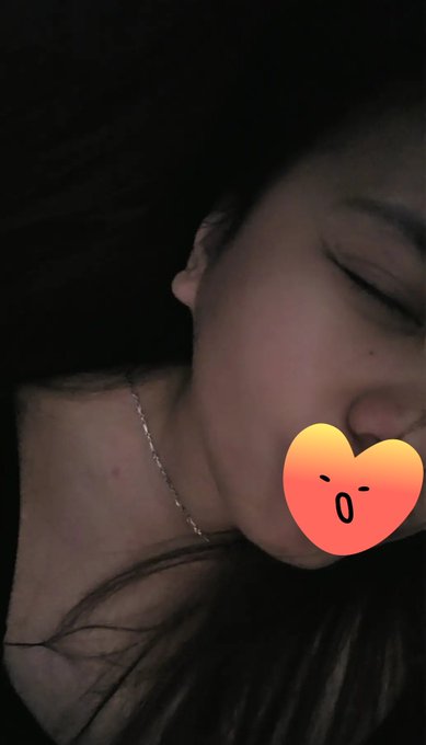 A dim, moody close-up photo of a sleeping person with a kissing emoji sticker placed over part of the face.