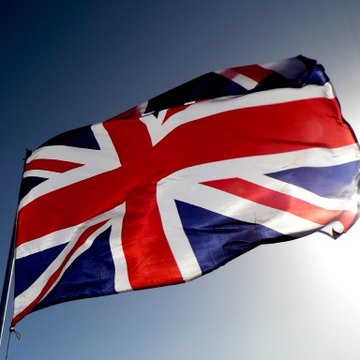 The Union Jack flag waves proudly against a clear blue sky, symbolizing the UK connection highlighted in the post's claim about XRP's significant presence in the region, with the ticker $XRP prominently referenced.