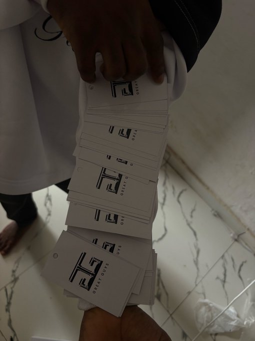 urn of white and black cards with "G" and "T" logos, arranged in a vertical line on a white marble floor.