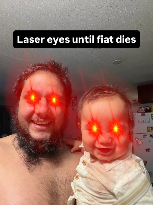 A humorous selfie of a bearded man holding a baby, both with digitally added red laser eyes, captioned 'Laser eyes until fiat dies' in a Bitcoin/crypto meme style.