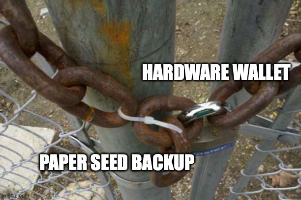 A meme using the 'two guys one chain' format to illustrate crypto security, labeled 'HARDWARE WALLET' and 'PAPER SEED BACKUP' linked together by a zip tie.