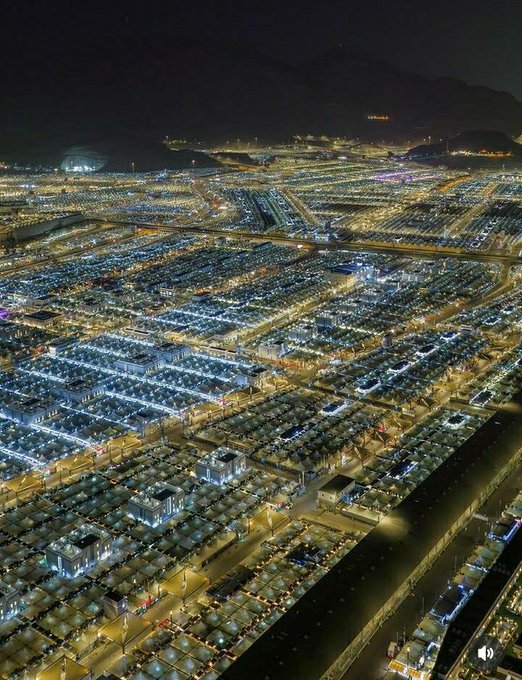 The image shows a city at night with numerous buildings lit up, creating an impressive skyline. The city appears to be densely populated, as there are many cars parked along the streets. The photo captures the essence of urban life and highlights the vibrant atmosphere that comes alive during nighttime hours in this bustling metropolis.