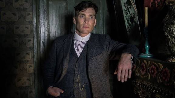 Cillian Murphy in a dark period suit leans against a mantelpiece, embodying the calm, vintage sophistication that contrasts with the high-stakes world of crypto markets referenced in the post.