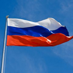 The Russian flag waves against a blue sky, symbolizing Russia's emerging role in regulated crypto trading, which is projected to surpass $46 billion in its first year according to Sberbank Deputy Chairman Anatoly Popov.