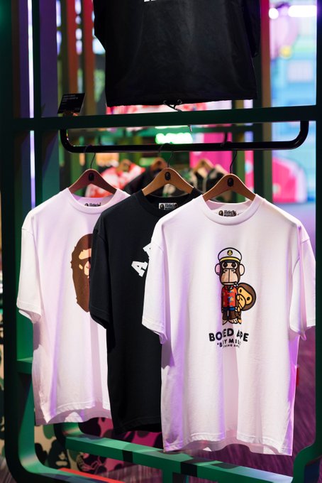 The image features three t-shirts hanging from a rack, each with different designs. One of them has a monkey design, while the other two have a more abstract or cartoonish style. The t-shirt with the monkey design is positioned on the left side of the rack, and the other two are located towards the right side. The post "BAYC is always a vibe" suggests that the t-shirts might be related to a specific subculture or fashion trend, such as hipster or alternative styles.