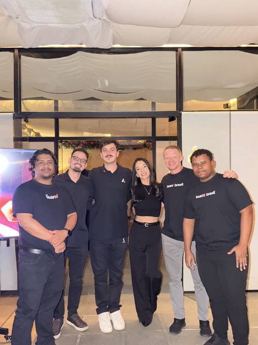 Six people pose together at the "Team1BR" Builders Dinner in Brazil, with five wearing black "team1" branded t-shirts and the woman in the center dressed in black, marking the start of the Builders Series just one week after their summit.