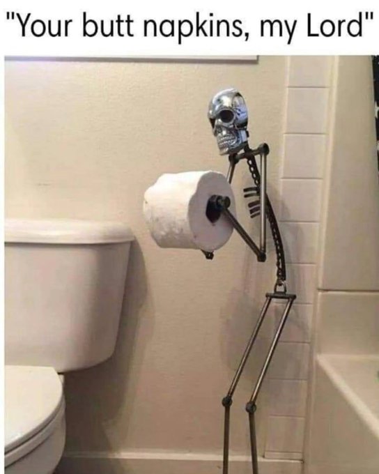 A skeleton-shaped toilet paper holder stands next to a toilet in a bathroom, humorously offering a roll of toilet paper with the caption "Your butt napkins, my Lord."
