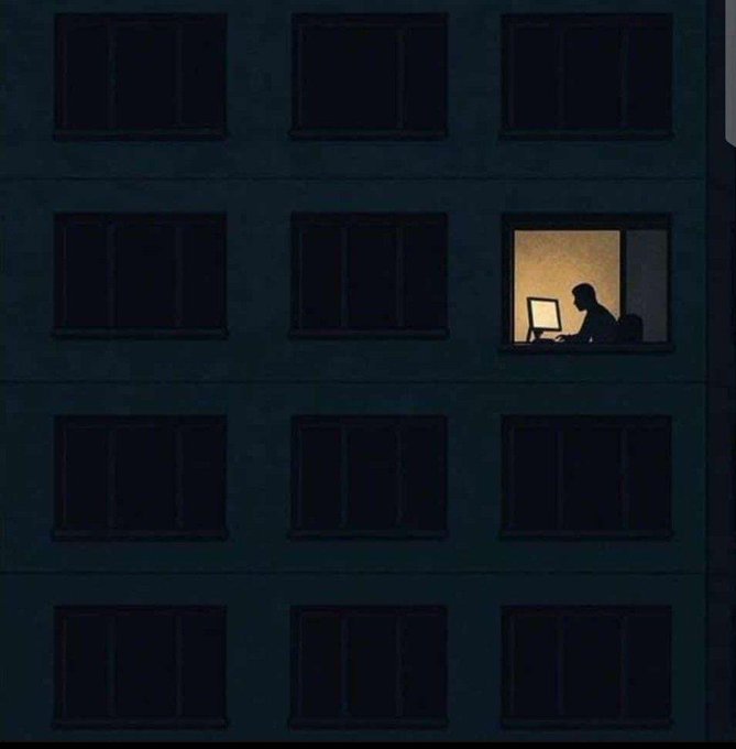 An illustration of a dark apartment building facade with multiple black windows, except for one illuminated window showing the silhouette of a person working at a computer.