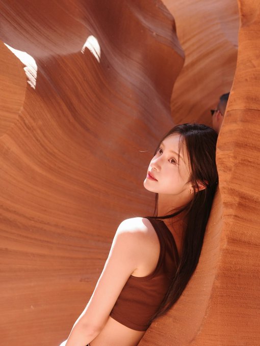 A woman with long dark hair poses thoughtfully against a backdrop of curved, orange sandstone slot canyon walls, wearing a brown top. The image appears unrelated to the accompanying post about Circle's cirBTC supply surpassing 5,000 units, serving instead as an aesthetic visual that contrasts the natural, organic canyon landscape with the technological/financial topic of cryptocurrency issuance.
