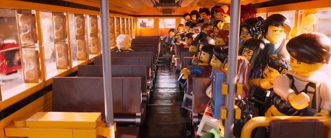 An interior view of a yellow school bus filled with numerous LEGO minifigure passengers seated on both sides of the aisle, with a single minifigure driver visible at the front.