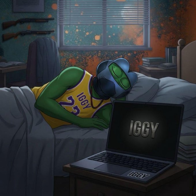 A digital illustration of a green alien character wearing a yellow Lakers jersey with 'IGGY' on it, sleeping in bed with a laptop displaying the 'IGGY' logo open on a nightstand, with rifles mounted on the wall.