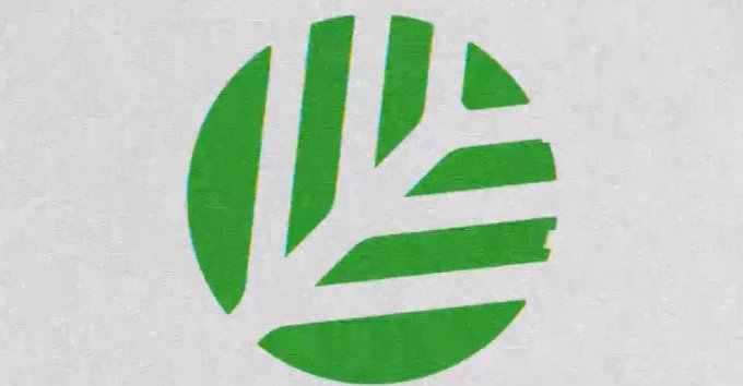 A close-up of a green globe logo with radiating lines, resembling the XRP cryptocurrency symbol, printed on a textured white surface.