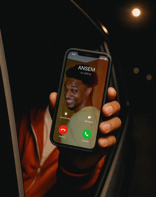 A hand holds a smartphone showing an incoming call from 'ANSEM is calling' with options to Message, Decline, or Accept, against a dark night background.