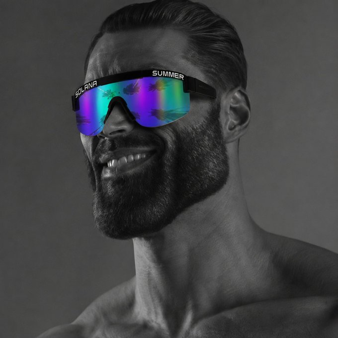 A black-and-white photo of a smiling bearded man wearing colorful iridescent sunglasses labeled 'SOLANA' and 'SUMMER'.