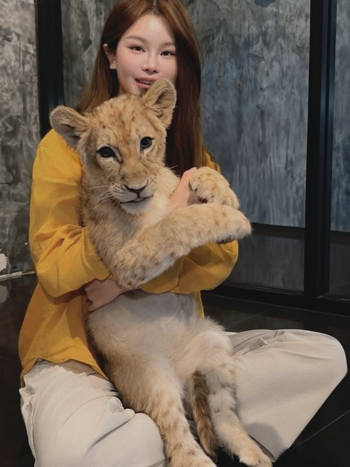 A woman smiles while holding a young lion cub in her arms. The image symbolizes "taming the beast" or gaining control over something powerful and wild—fittingly representing how Binance VIP upgrades help clients tame the volatile crypto market and manage their wealth more effectively.