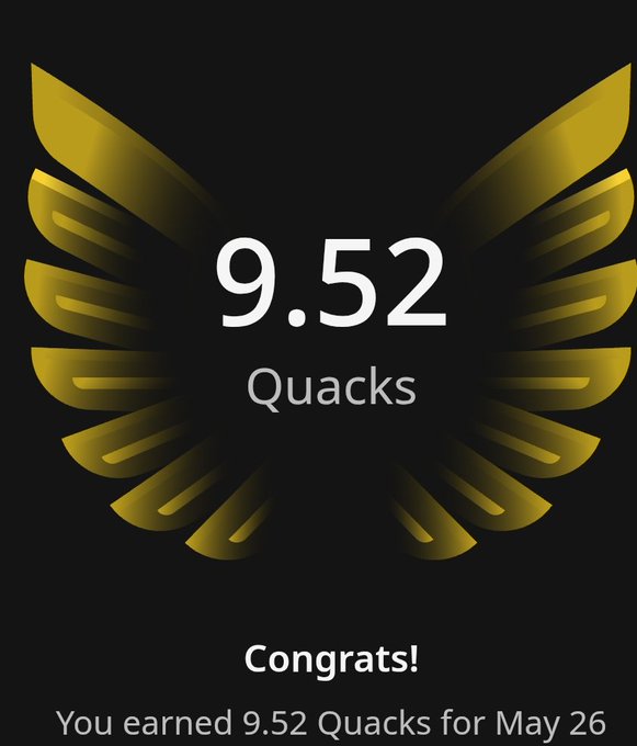 The image features an award for Quacks, with a gold bird's wing design at the top of the frame. Below this, there are two lines of text that read "Congratulations! You earned 9.52 Quacks for May 26". The background is black and has a gradient effect on it, giving it a shiny appearance.