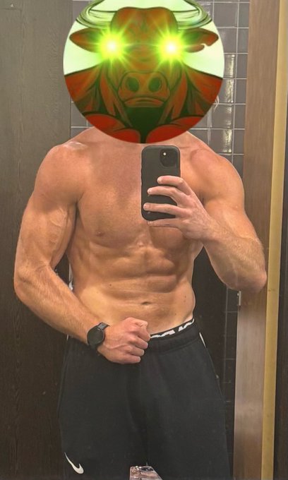 The image features a shirtless man taking a selfie with his phone, likely capturing his impressive physique as he flexes his muscles. The photo has been edited to include a green bull's eye effect at the top of the frame, giving the impression that the man is wearing a bullseye on his head. This creative editing adds an element of fun and humor to the image while still conveying the message about the importance of fitness and discipline in one's life.