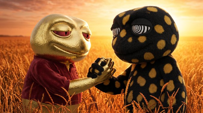 Two surreal, 3D-animated characters—one golden and round, the other black with yellow polka dots and spiral eyes—stand in a wheat field at sunset holding hands.