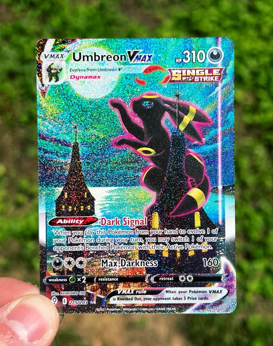 A hand holds a holographic Umbreon VMAX Pokémon card (HP 310, card #215/202) against a leafy background, showcasing its shimmering rainbow foil finish. The "Get Mooned" caption playfully references the card's moonlit artwork featuring Umbreon under a full moon.