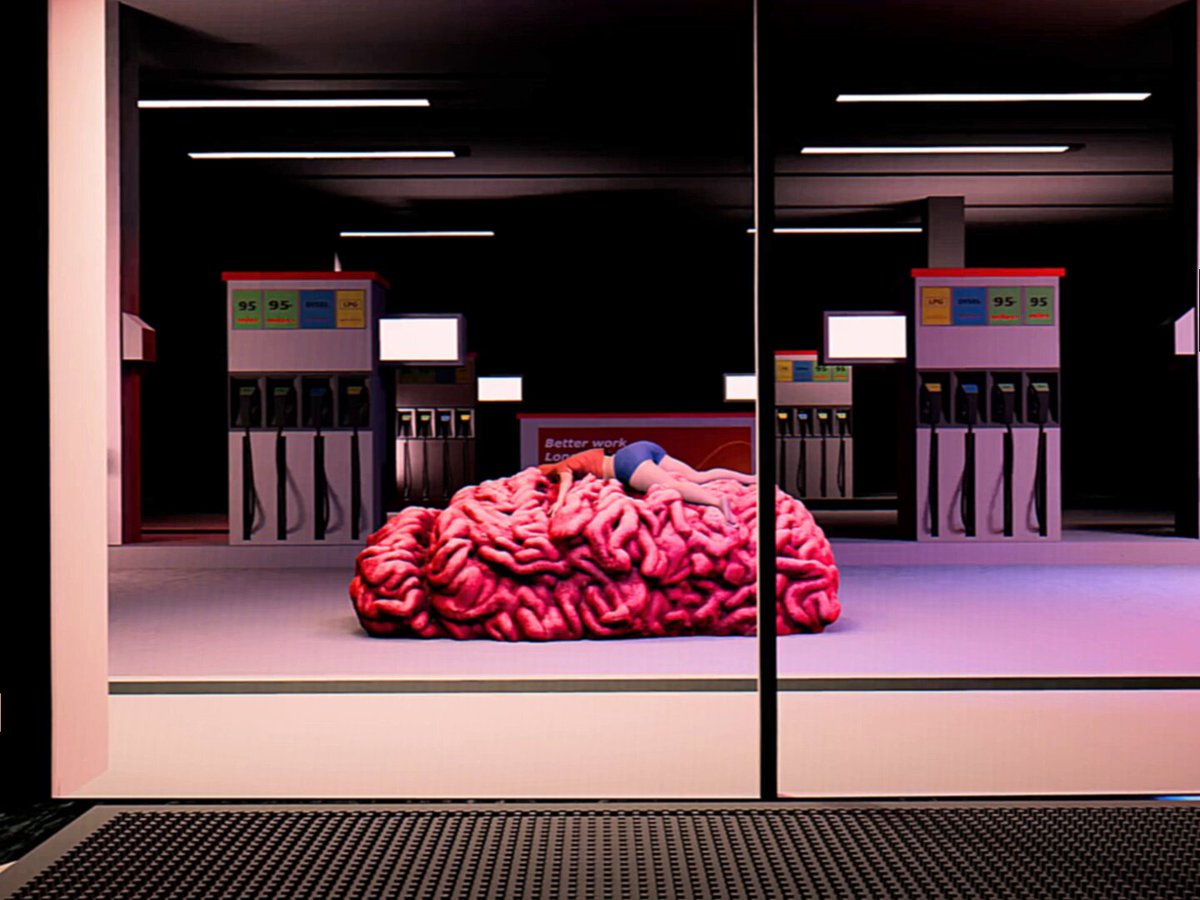 The image features an advertisement for gas stations, with a large pink brain-shaped object sitting inside one of them. The brain appears to be made out of human tissue or parts, giving it a creepy and unsettling appearance. The brain is placed on a white floor in front of two gas pumps, creating a striking contrast between the organic form of the brain and the mechanical nature of the gas station equipment.