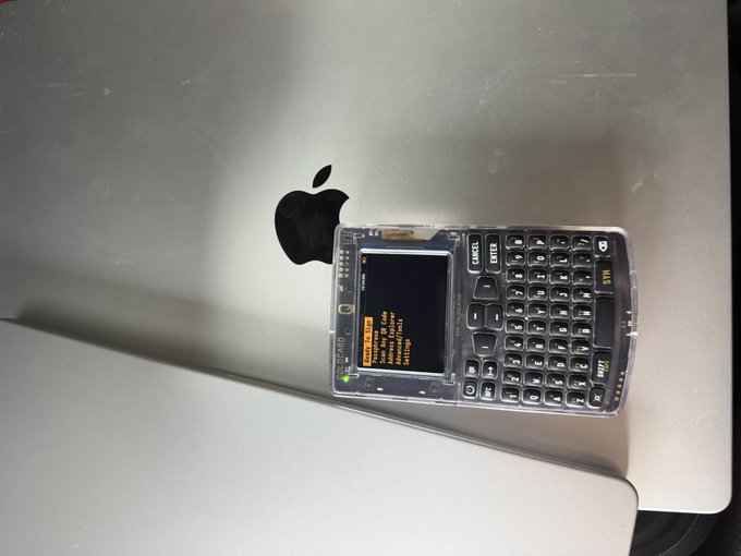 A transparent-cased PDA-style device with a full QWERTY keyboard sits on top of a silver laptop with an Apple logo. The accompanying post about migrating family savings into multi-institution custody reinforces the image's nod to technological self-custody and financial sovereignty, aligning with the post's Bitcoin themes.