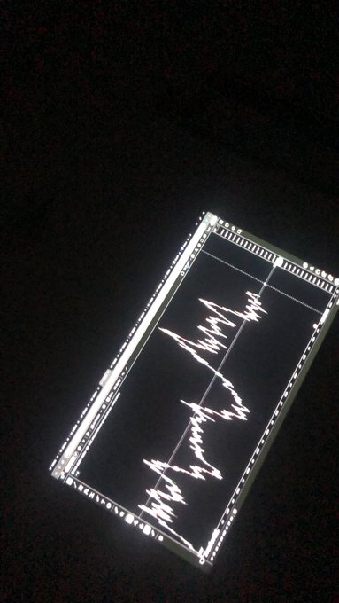 A tilted digital display screen shows a white audio waveform pattern against a black background.