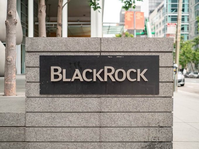 The image shows a stone monument displaying the "BlackRock" name in metallic lettering, marking the entrance to the company's building. The sign connects to the article by highlighting BlackRock as one of the major financial firms joining a $15 million initiative with Coinbase and Strategy to safeguard Bitcoin against future quantum computing threats.