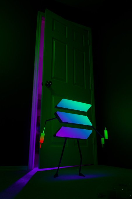 Digital illustration of a green stick-figure character with colorful neon panels for a body standing in a doorway lit with green and purple light, holding small glowing objects.