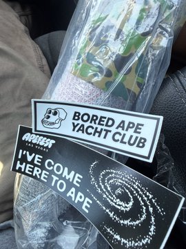 Bored Ape Yacht Club merchandise including stickers with the BAYC logo and phrases 'BORED APE YACHT CLUB' and 'I'VE COME HERE TO APE', packaged in a clear plastic bag.